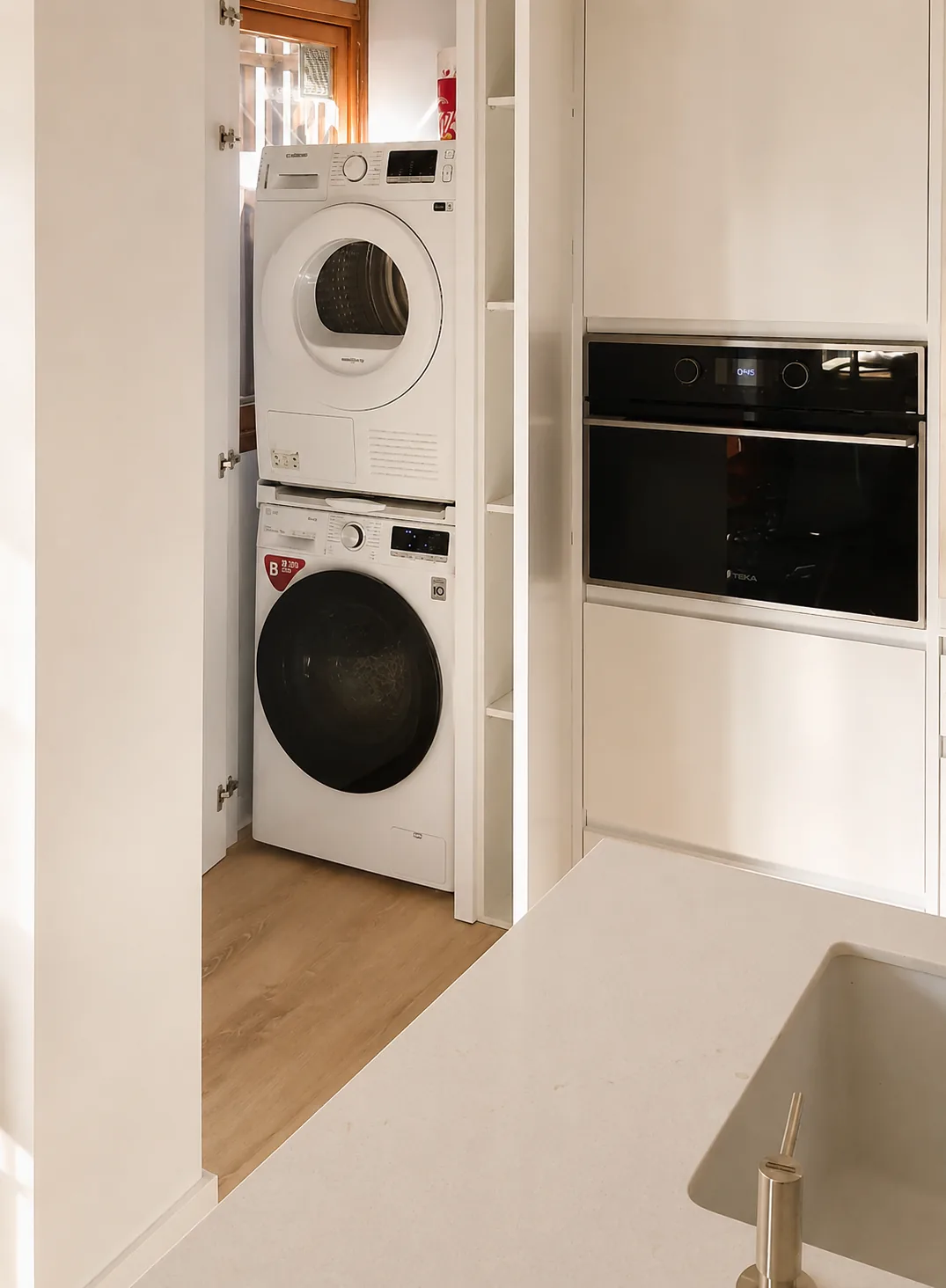 Cocina blanca abierta al salón con isla y lavadero integrado