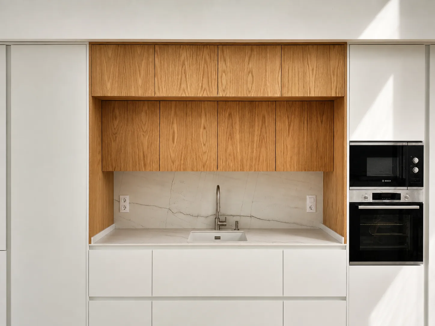 Una cocina blanca y de roble abierta a un espacio lleno de luz