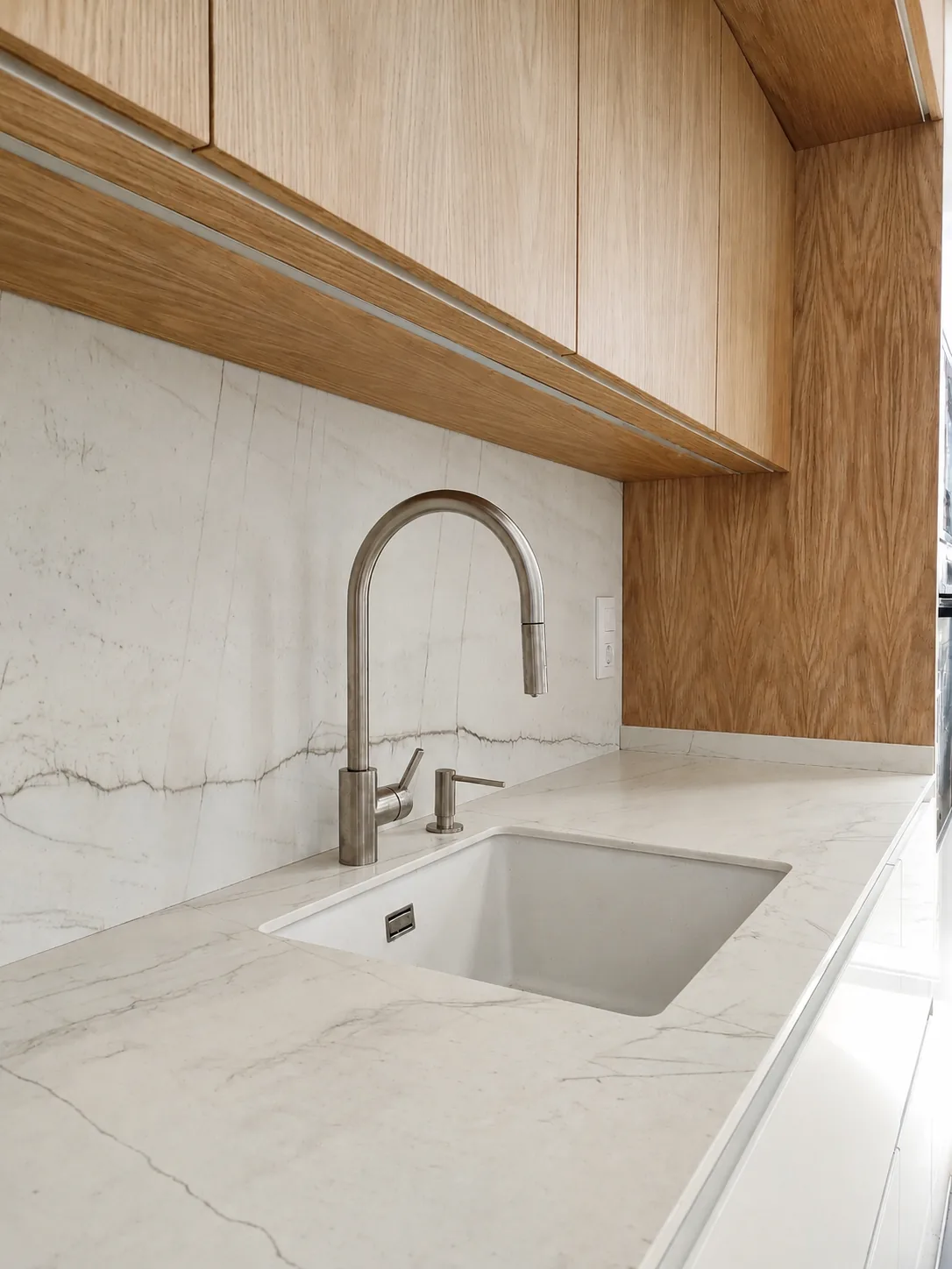 Una cocina blanca y de roble abierta a un espacio lleno de luz