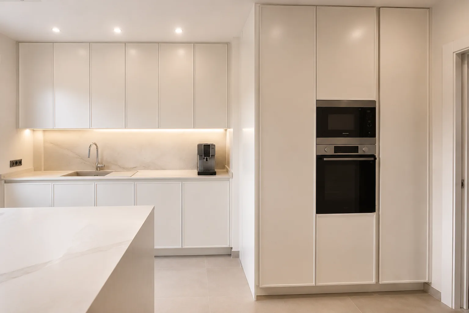 Una cocina en cashmere conectada al salón con madera y cristal