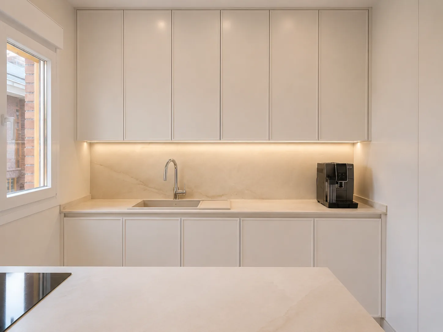 Una cocina en cashmere conectada al salón con madera y cristal