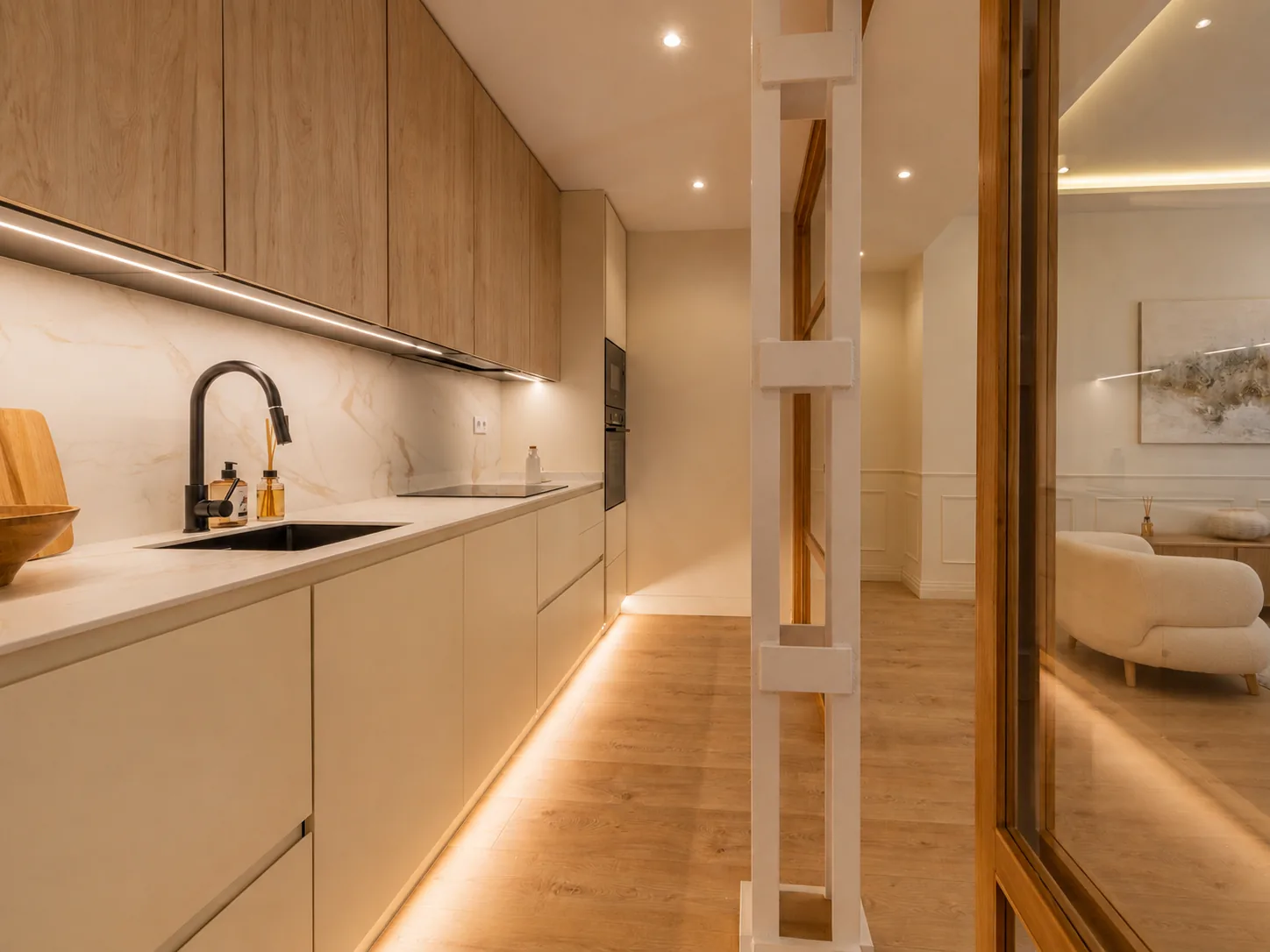 Cocina integrada en el pasillo con acabados en madera clara y crema